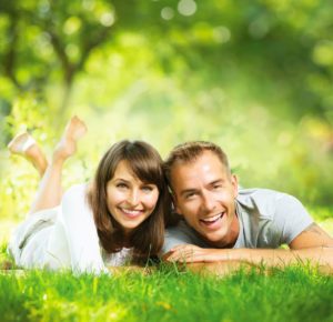 happy smiling couple together relaxing on green grass outdoor