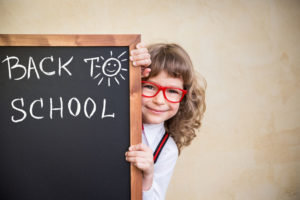 school kid in class. happy child holding blackboard blank. 