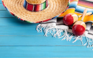 Mexican sombrero and maracas with traditional serape blanket laid on an old blue painted pine wood floor. space for copy.